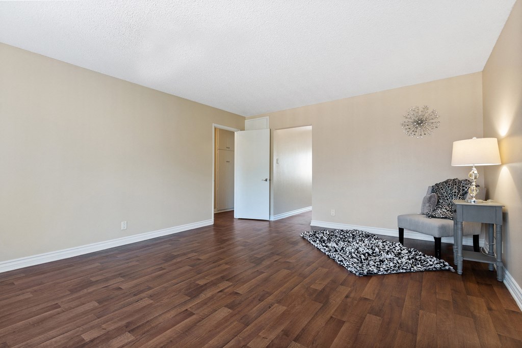 an empty living room with hard wood flooring and a chair and table at Terramonte Apartment Homes, Pomona, California