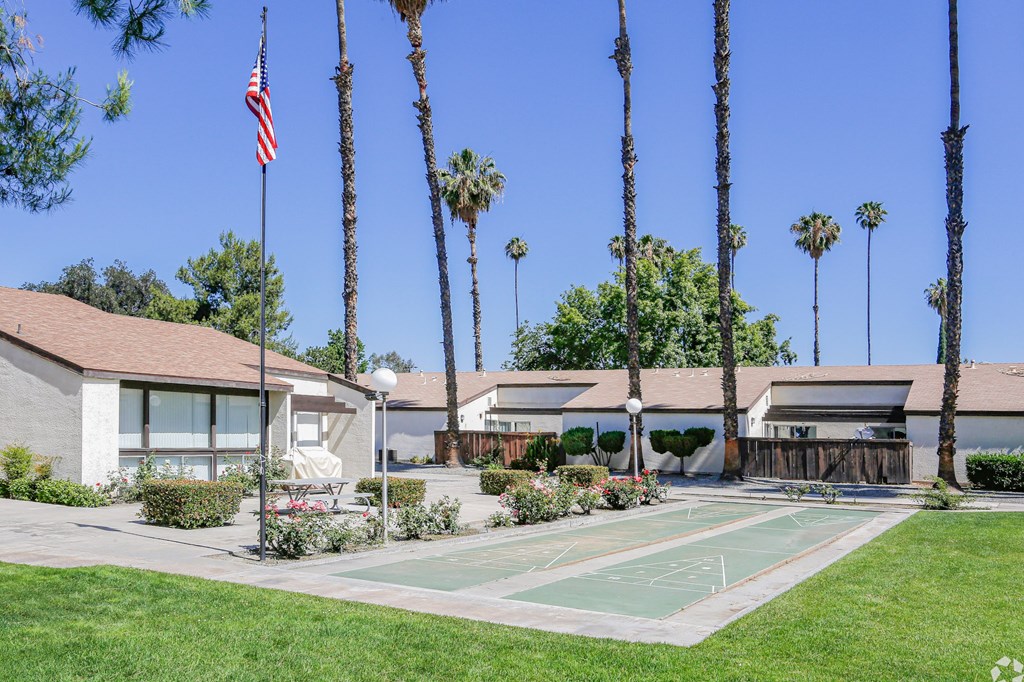 A flag is flying in front of a building with palm trees.