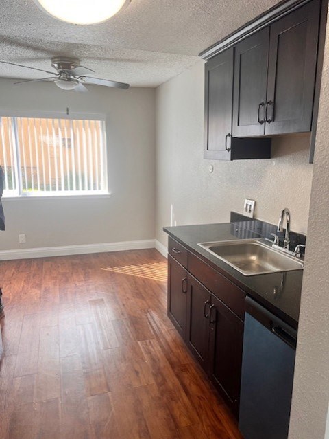 A kitchen with wooden floors and a stainless steel sink.