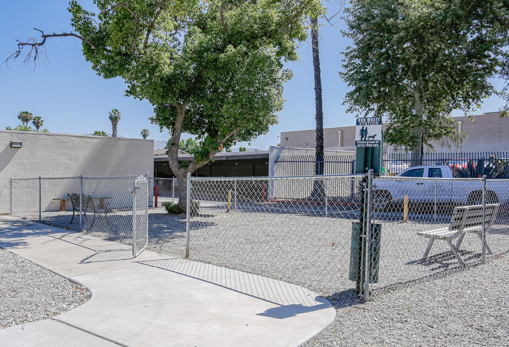 A park with a fence, bench, and trees.