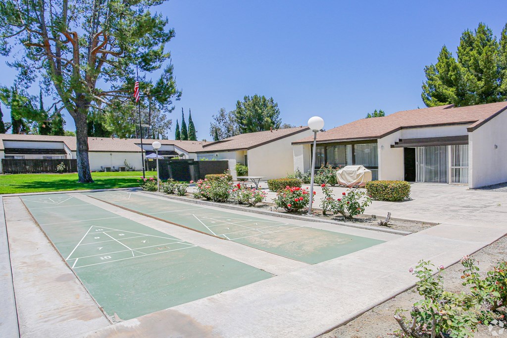 A basketball court is located in the middle of a courtyard with a building in the background.
