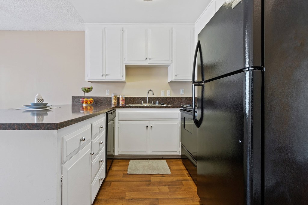a kitchen with white cabinets and a black refrigerator at Terramonte Apartment Homes, Pomona