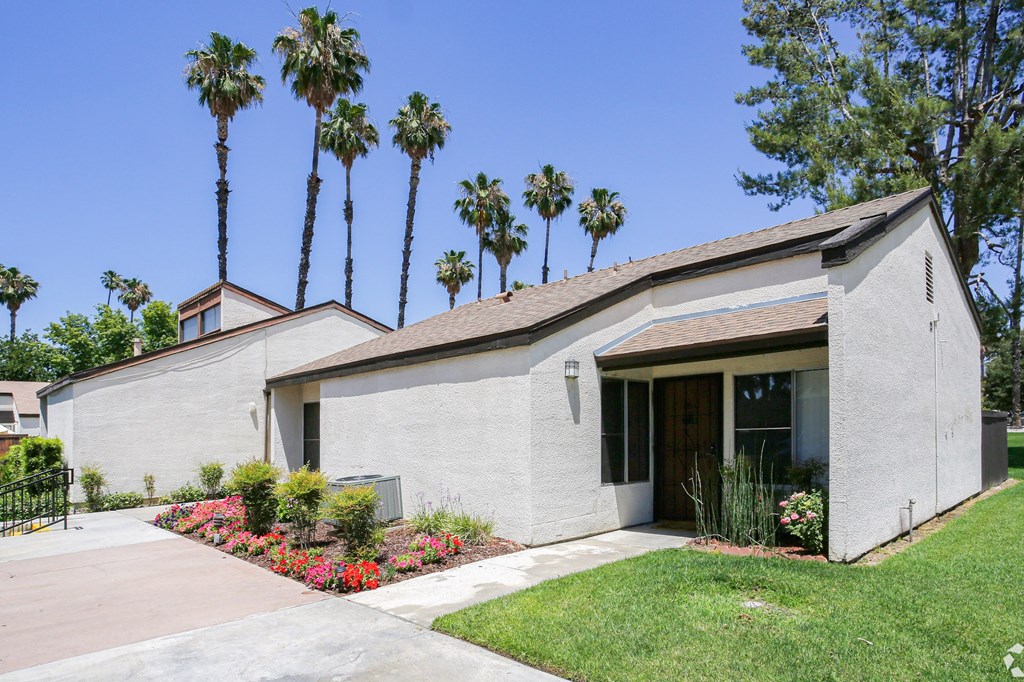 A house with a brown roof and a white wall with a brown door and a window.
