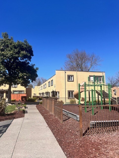 A playground with a slide and a building in the background.