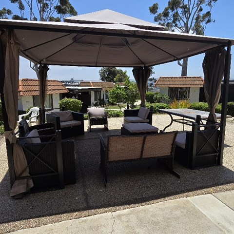 A patio with a white canopy and black chairs.