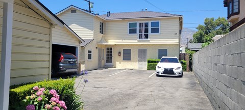 A white car is parked in a driveway in front of a house.