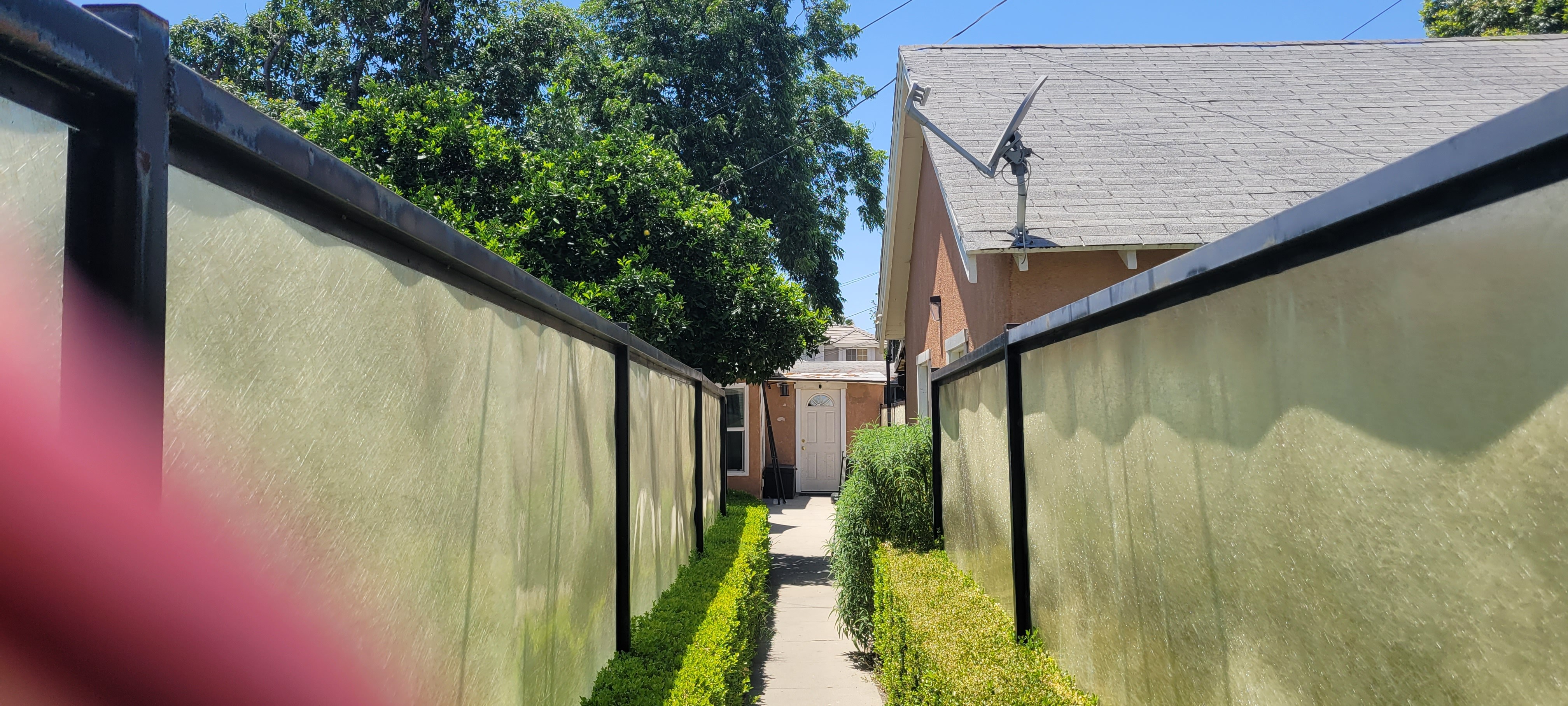A narrow alley with a wall on one side and a house on the other.