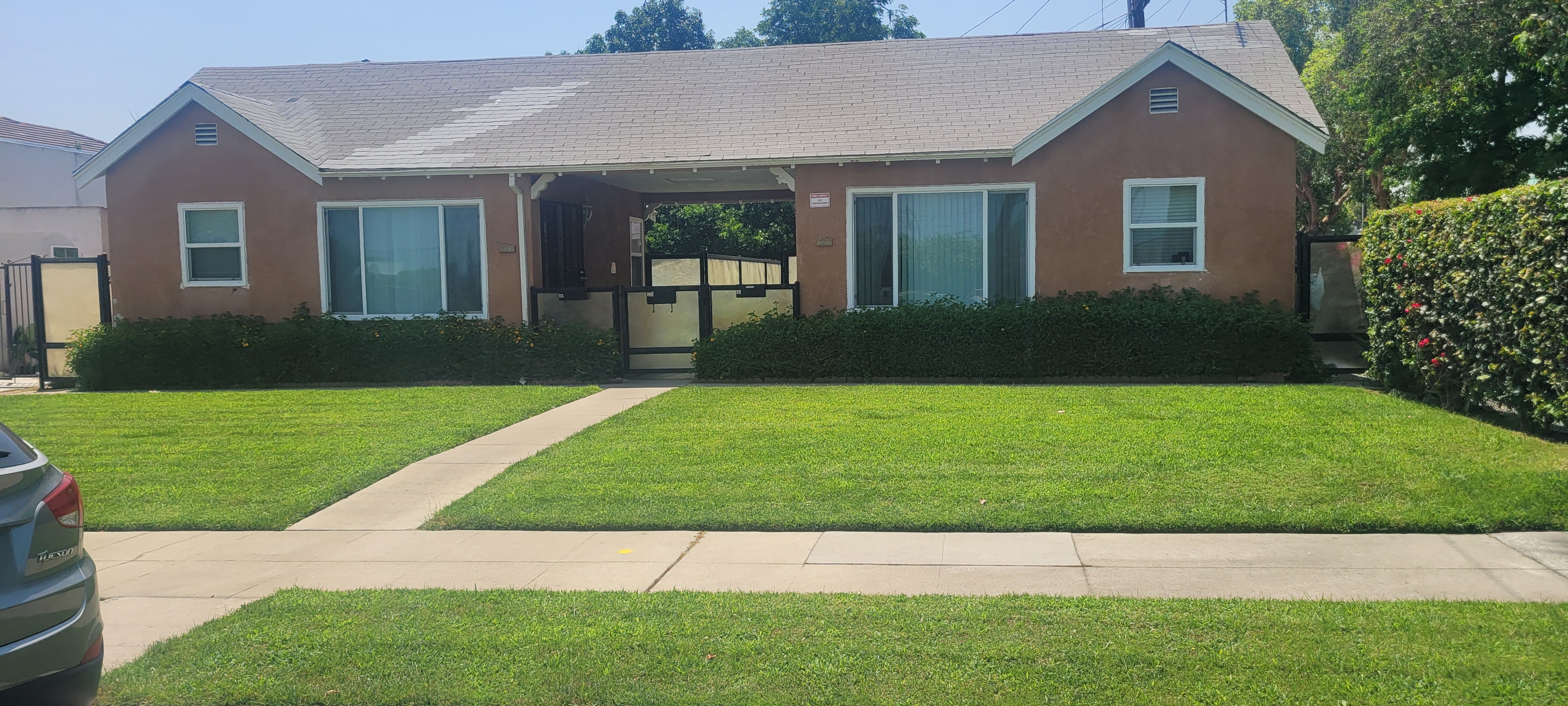 A small house with a brown roof and a green lawn in front.