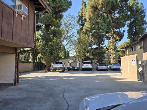 A parking lot with cars and a building with an air conditioning unit.