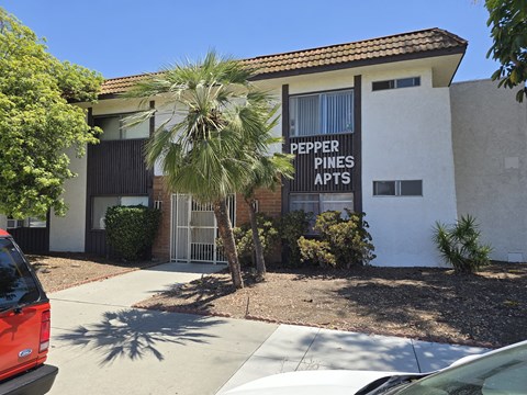 A Pepper Pines Apts sign is on the front of a building.