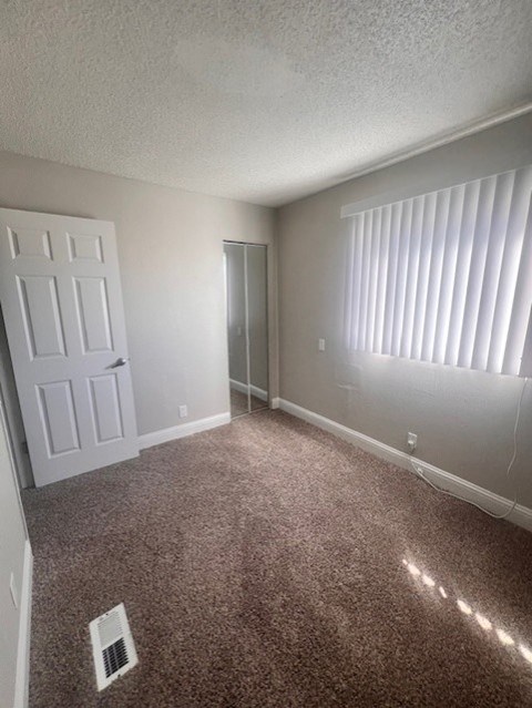 A room with a carpeted floor and a window with blinds.