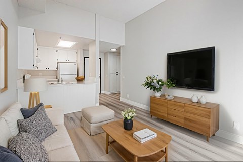 A living room with a white couch, a wooden coffee table, and a flat screen TV mounted on the wall.