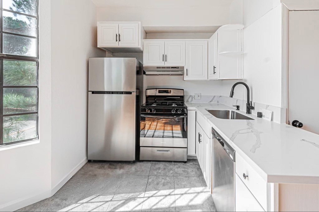 A modern kitchen with white cabinets and a stainless steel refrigerator.