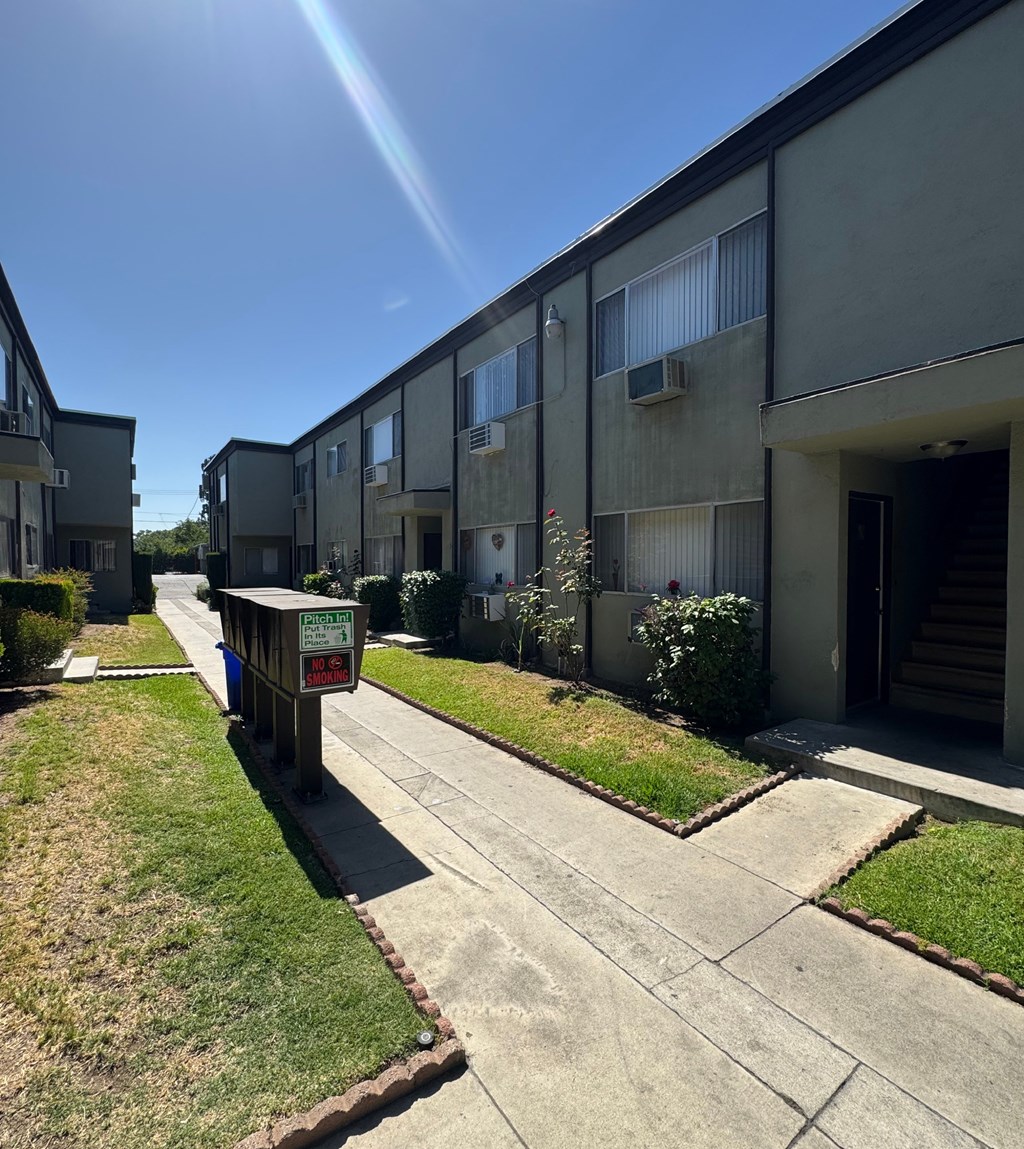 A sunny day at the apartment complex with a sign in the foreground.