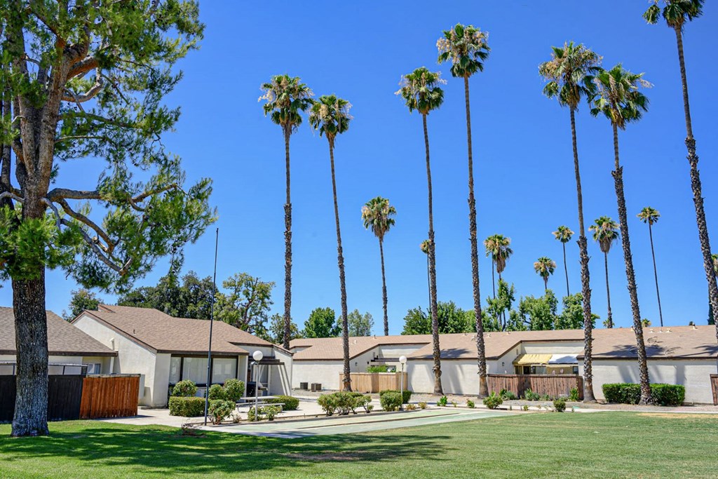 A row of palm trees in front of a house.