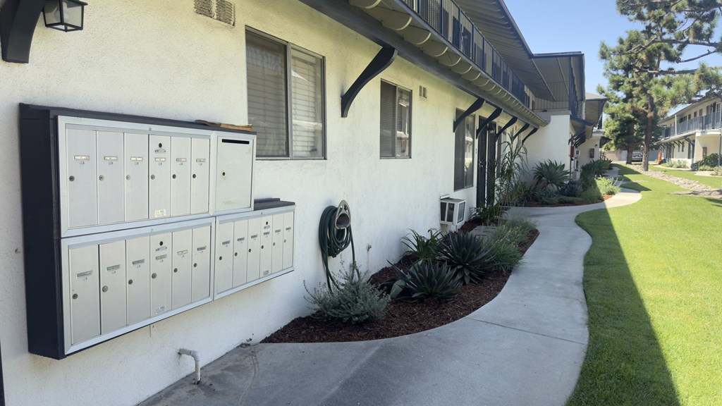 A white house with a black mailbox and a green lawn.
