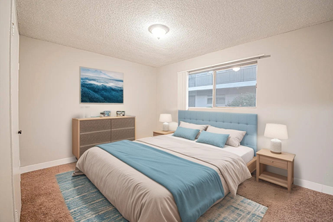 A bedroom with a bed, nightstand, and a painting on the wall.