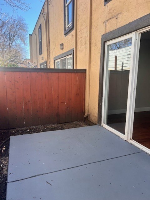 A wooden fence is in front of a tan building.