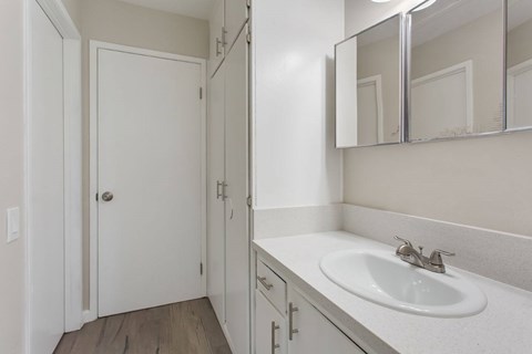 A white bathroom with a sink and mirror.