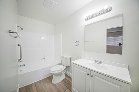 A white bathroom with a toilet, sink, and mirror.