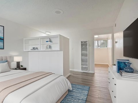 A bedroom with a large bed and a TV on the wall.