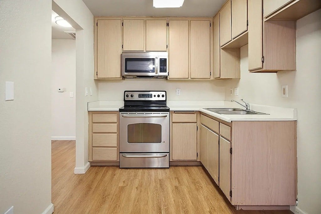 A kitchen with wooden cabinets and a stainless steel stove.