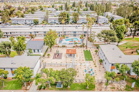A large white building with a pool in the middle of a grassy area.