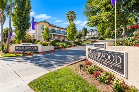 A sign for Amberwood Apartments is displayed in front of a building.