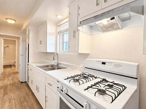 A white kitchen with a stove and sink.
