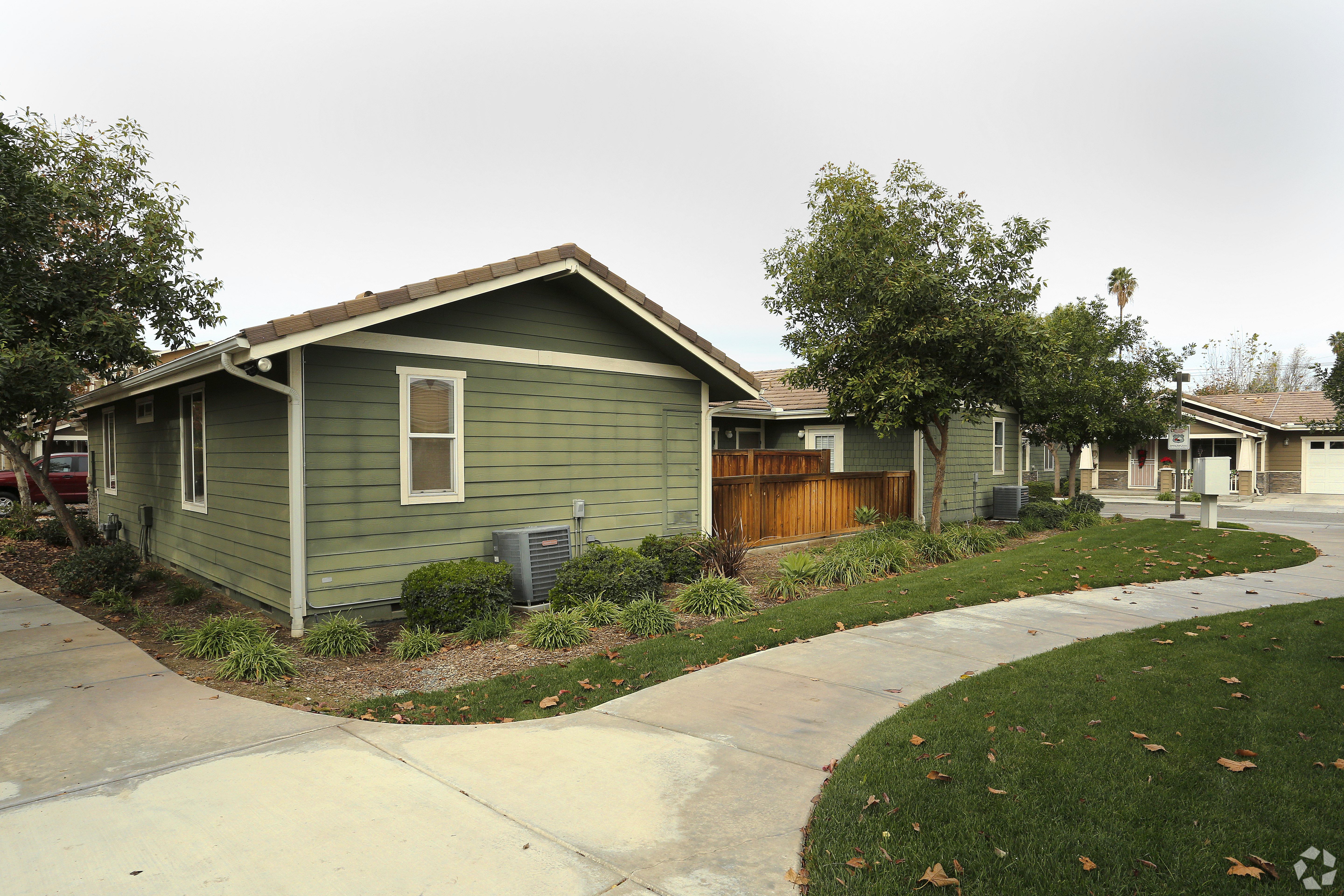 A green house with a brown fence and a grey roof.