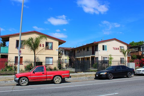 A red pickup truck is parked on the side of the road in front of a house.