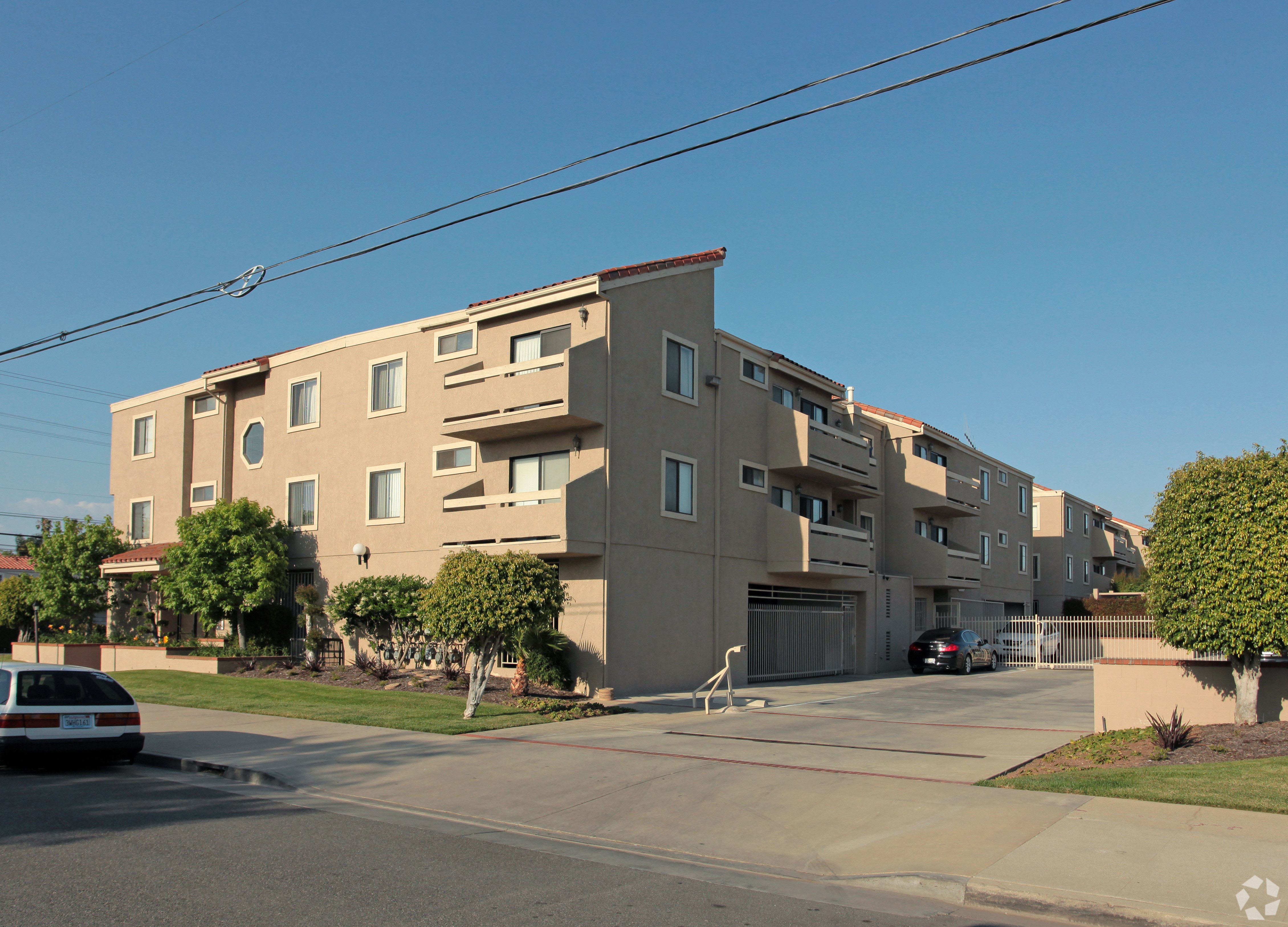 A beige apartment building with a car parked in front.