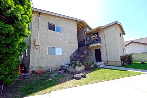 A tan house with a black door and a balcony.