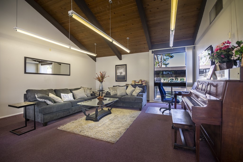 A living room with a couch, a coffee table, and a piano.