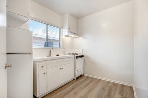A small kitchen with white cabinets and a window.