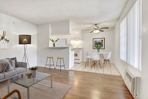 A living room with a grey sofa, a glass coffee table, and a bar area with stools.