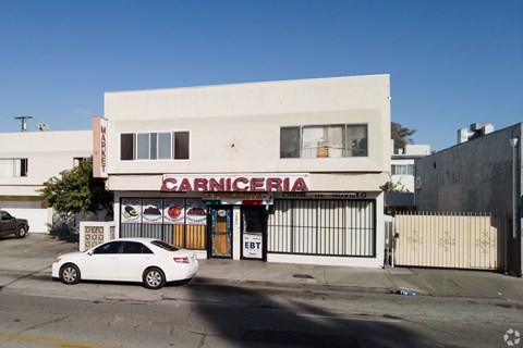 A white car is parked in front of a Carnicería.