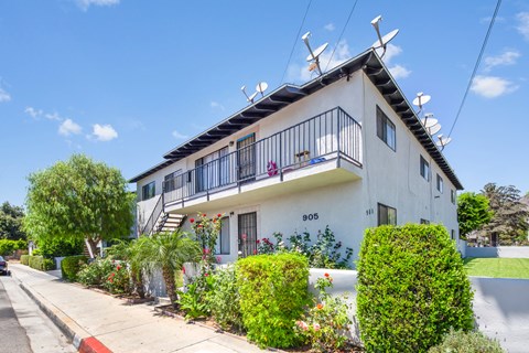 A white house with a balcony and a black railing.