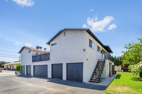A white two-story house with a black roof and a grey garage door.