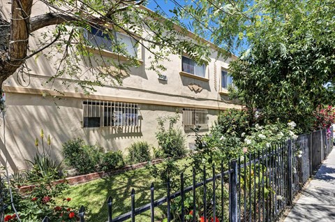 A house with a black fence and green plants in front.