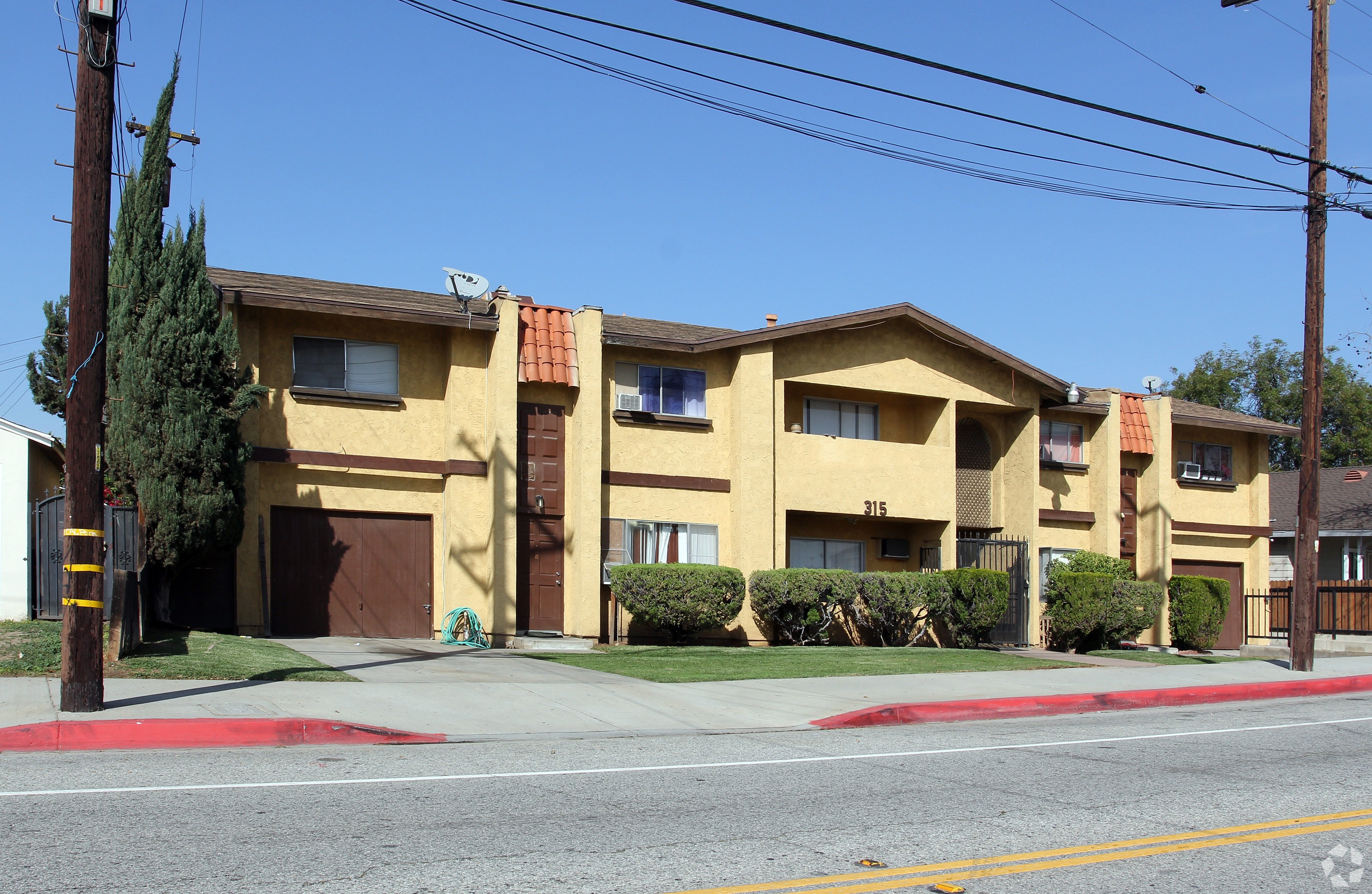 A yellow building with a red roof and a brown garage door.