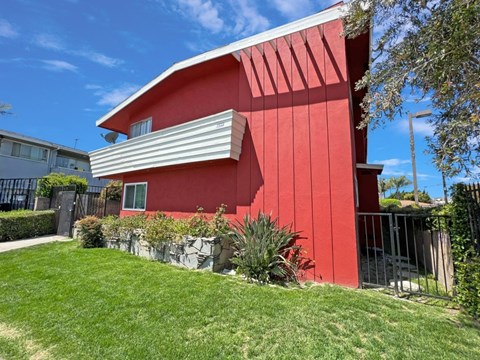 A red house with a white roof and a green lawn in front.