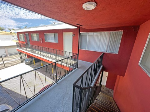 A red building with a balcony and a black railing.