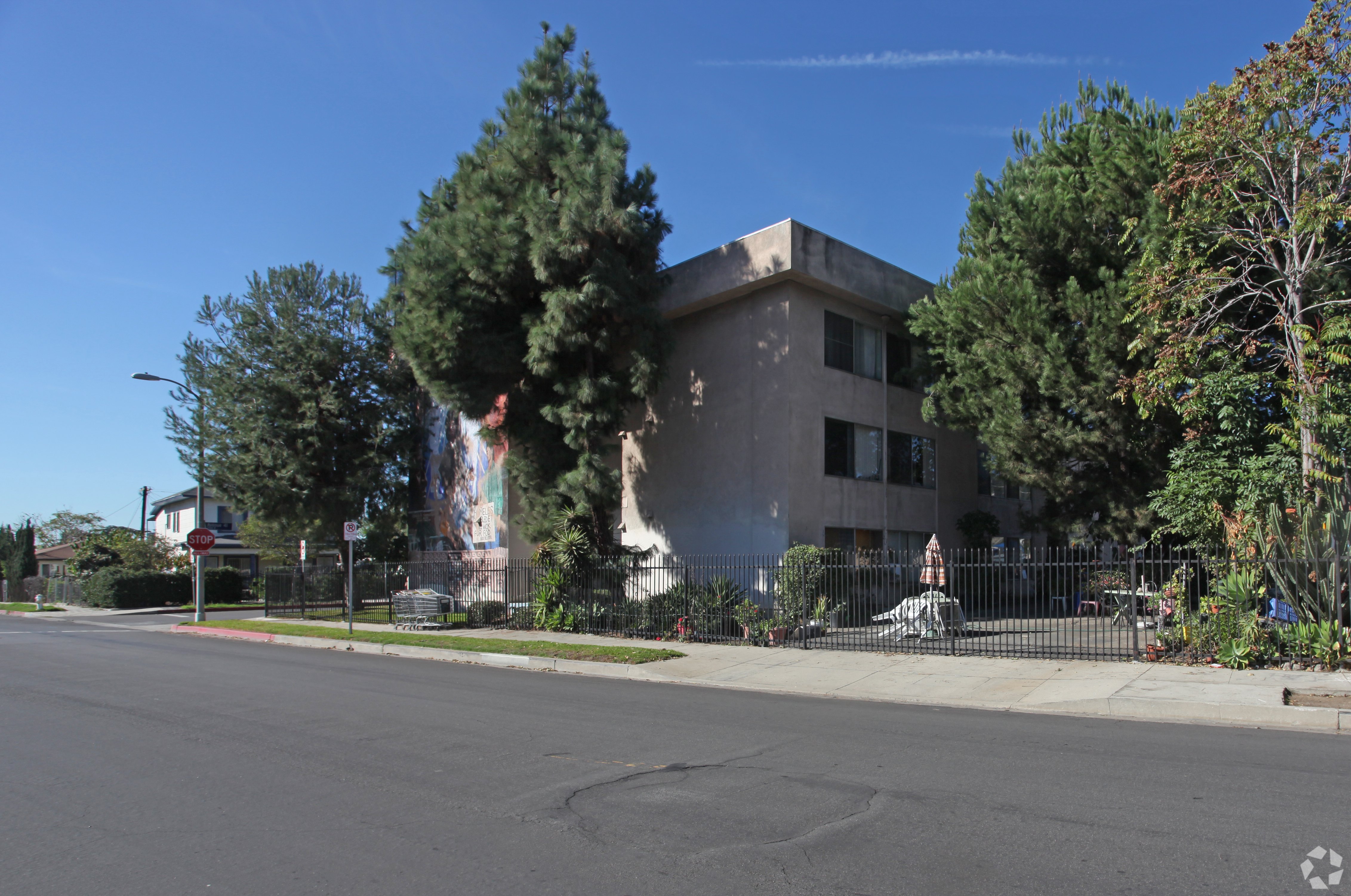 A modern building with a grey facade is surrounded by trees and a clear blue sky.