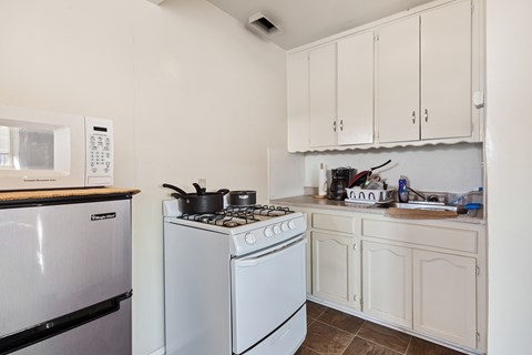 A white stove sits in a kitchen with a white oven and white cabinets.