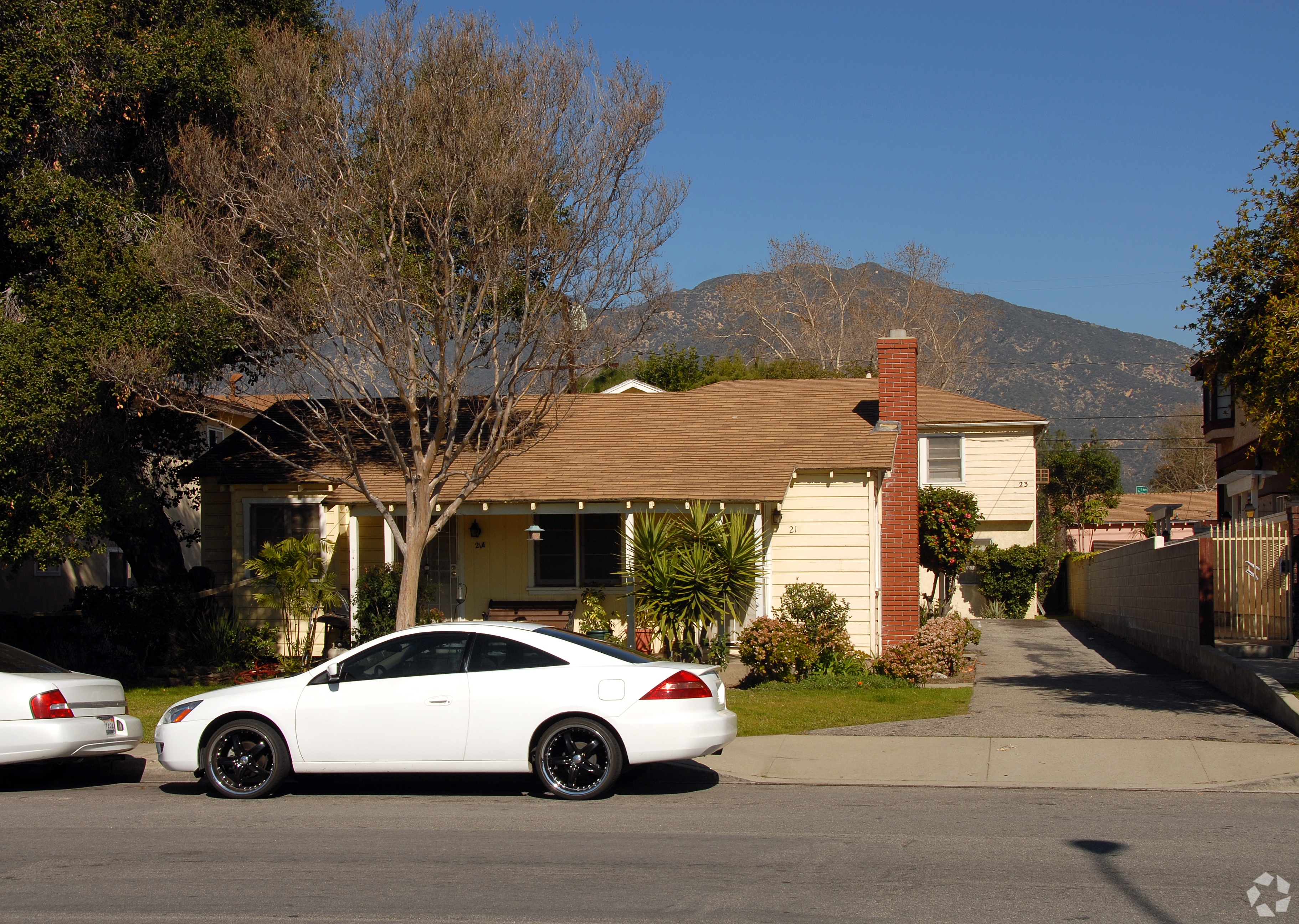 A white car is parked in front of a house.