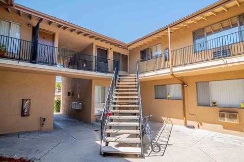 A bicycle is parked on a concrete patio in front of a staircase.