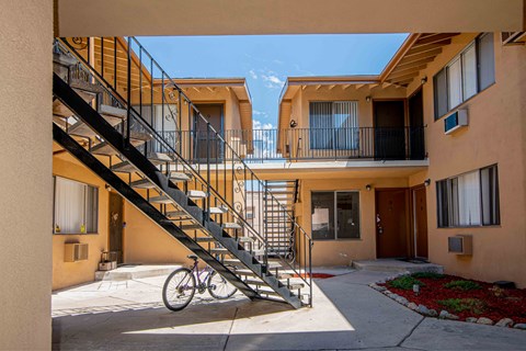A bicycle is parked on a concrete path in front of a staircase.