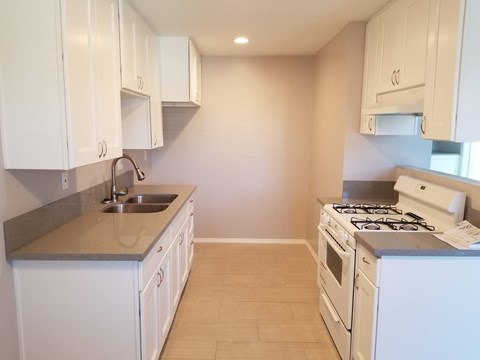 A kitchen with white cabinets and a stove top oven.