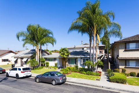 A row of houses with cars parked in front.